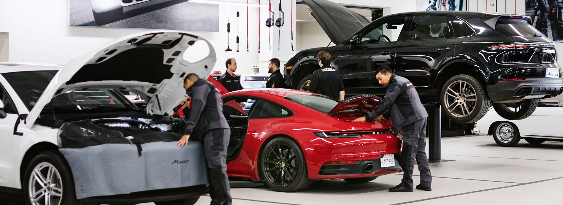 Car mechanics servicing vehicles in an auto repair shop.